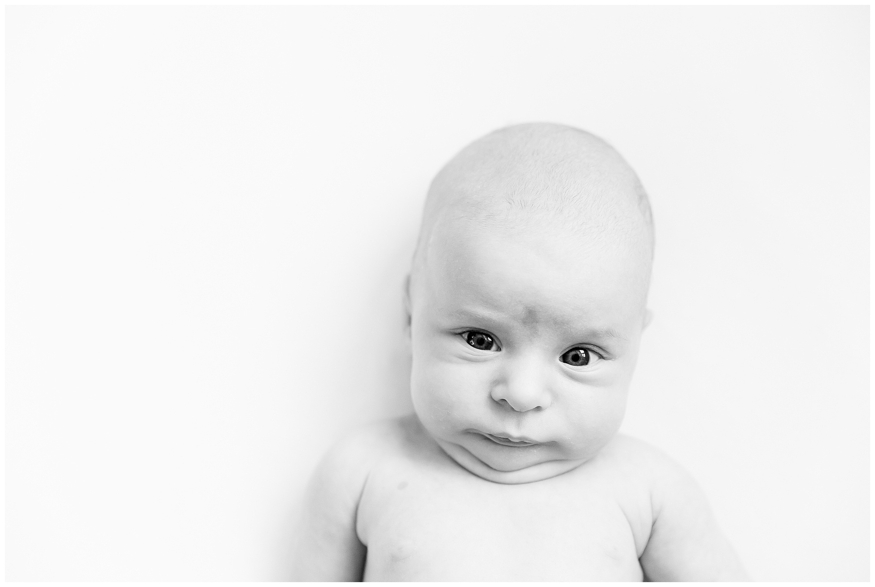 Close-up black and white portrait of a serious-looking baby with furrowed brow