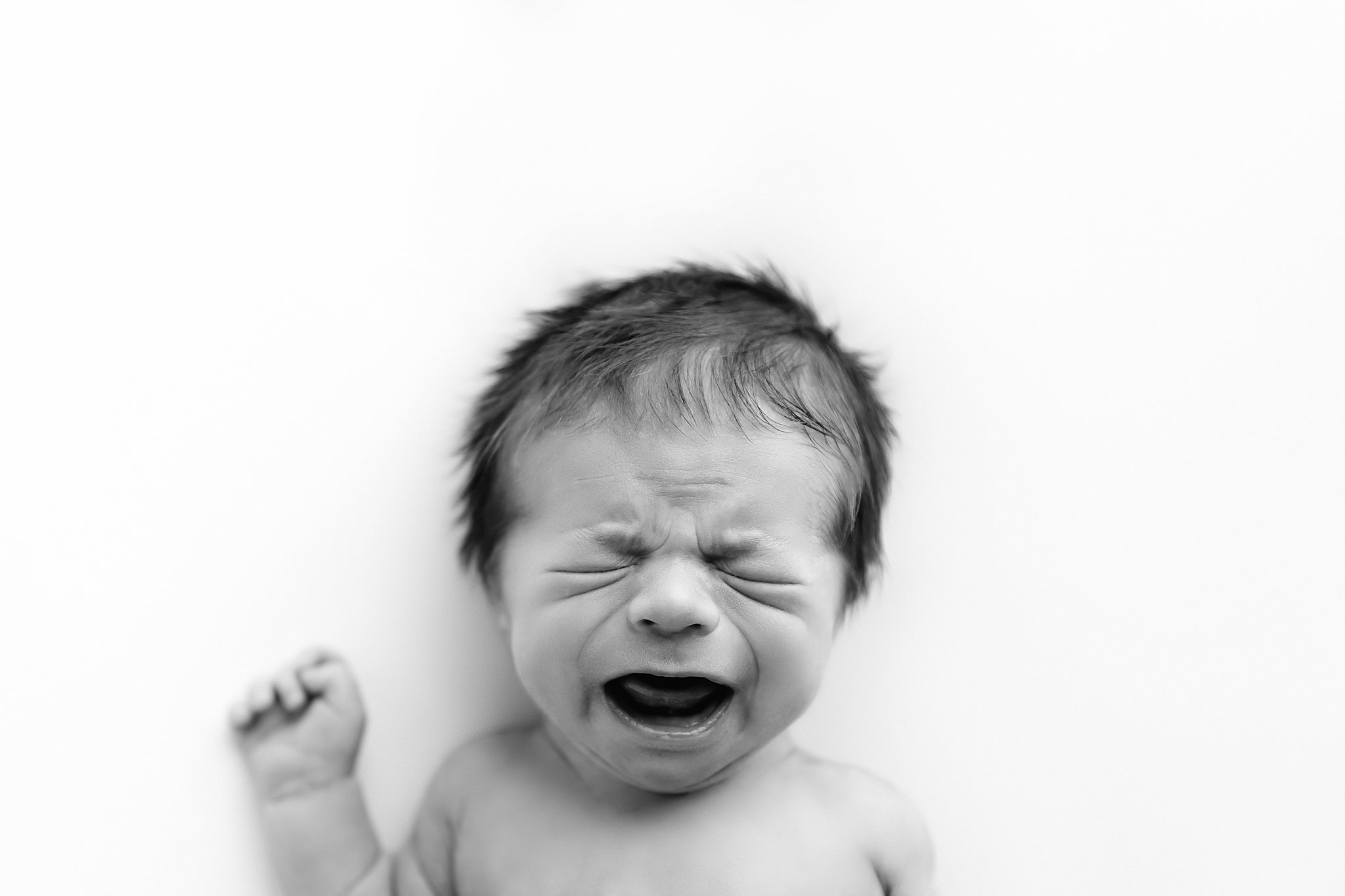 Black and white portrait of crying newborn illustrates challenges in photography client workflow